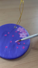 Load and play video in Gallery viewer, hand painting pink cherry blossoms on purple Christmas ornament
