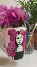 Load and play video in Gallery viewer, Video of Hand painted mug showing the illustration of a woman surrounded by peonies. The peonies wrap around the mug 

